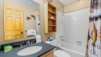 A bathroom with a double sink, toilet, bathtub, and shower curtain.