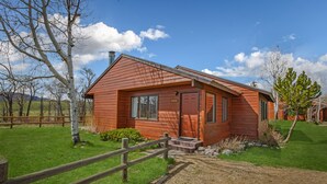 A wooden cabin with a red door, a front porch, and a gravel driveway. - Fish Hook - Cozy cabin tucked in the mountains (Clark)