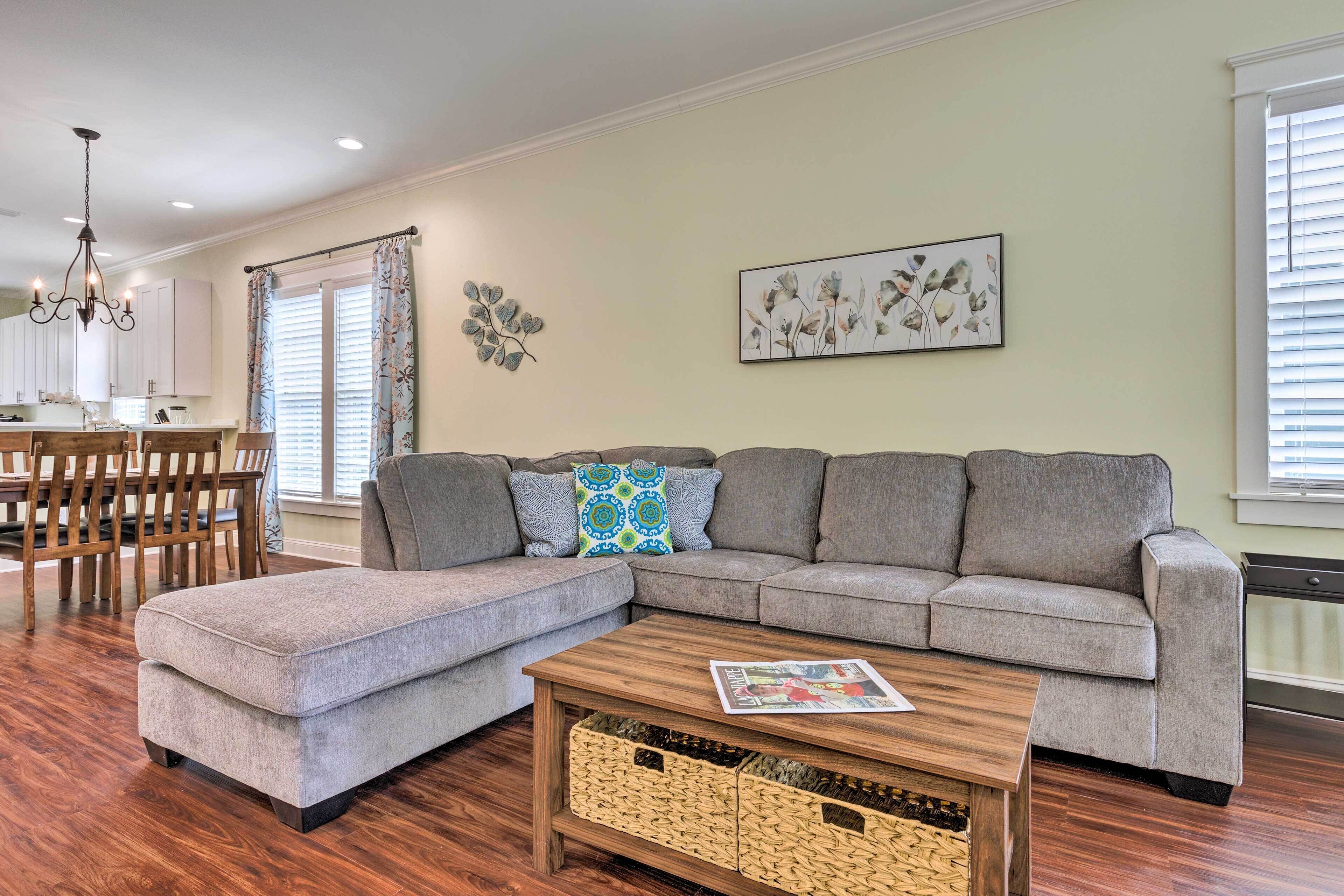 A living room with a sectional sofa, ottoman, coffee table, and wicker baskets.
