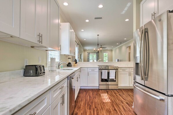 A modern kitchen with white cabinets, stainless steel appliances, and a wooden floor. - 2 Mi to Dauphin St! Charming Home in Mobile (Mobile)
