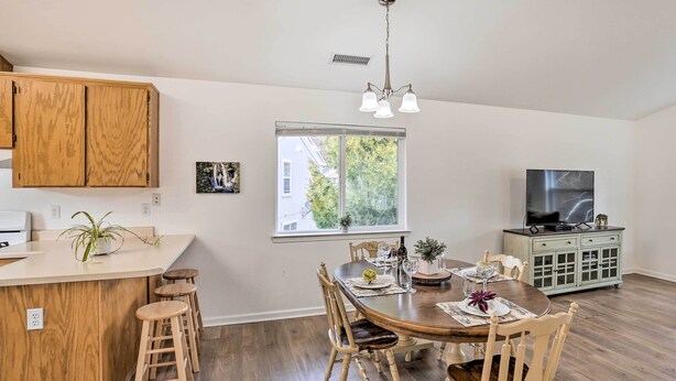 Una cocina moderna con armarios de madera, una barra y una mesa de comedor para cuatro.