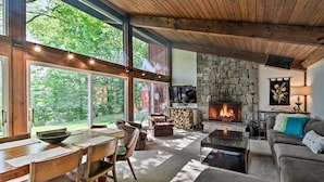Un salón amplio con chimenea de piedra, ventanas grandes y una zona de estar acogedora.