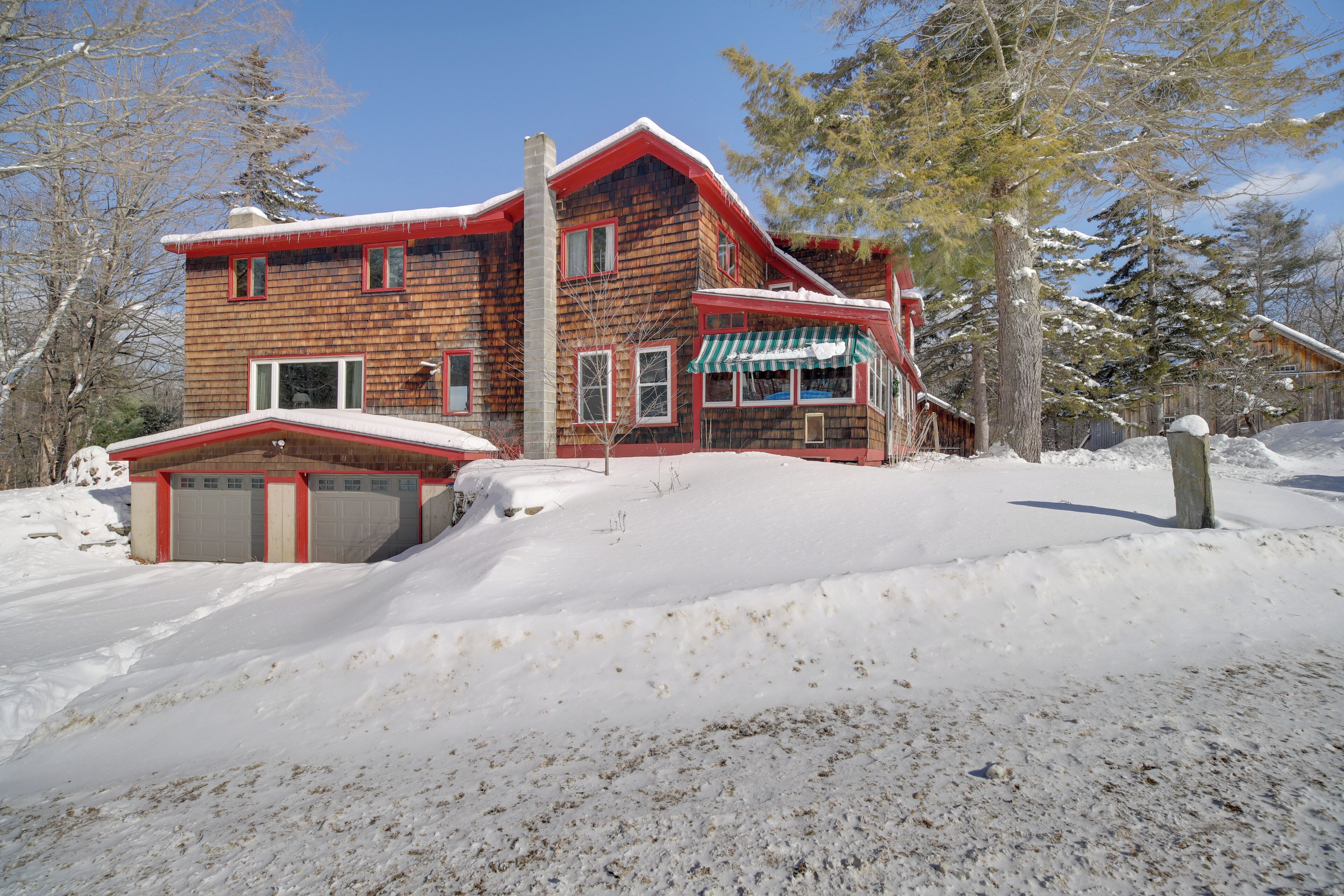 A wooden house with a red roof and a garage.