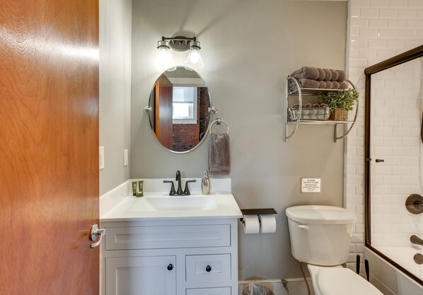Une salle de bain avec un lavabo blanc, un miroir, un porte-serviettes et des toilettes.