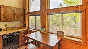 A kitchen with wooden cabinets, a dishwasher, a coffee station, and large windows with a view of trees. - Cozy Studio Near Hiking & Skiing, Walk to Downtown (Mount Shasta)