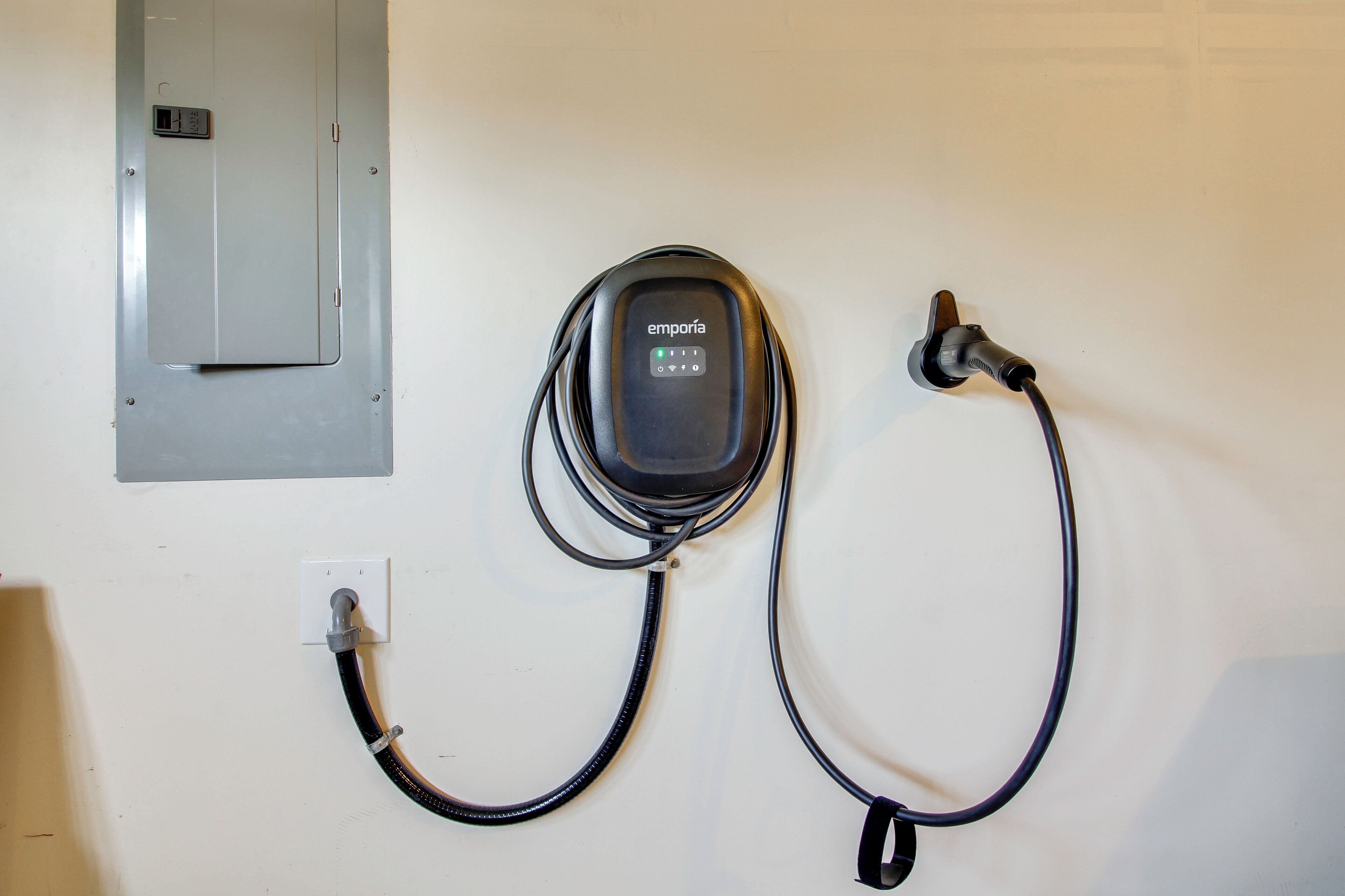 Une boîte électrique fixée au mur, avec un câble relié à une prise.