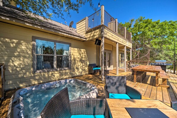 Una casa de dos pisos con jacuzzi, mobiliario exterior y terraza.