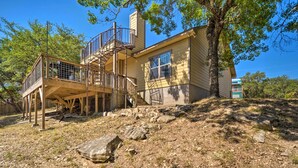 Une maison à deux étages avec une terrasse en bois et un escalier menant à un balcon.