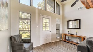 A spacious room with a large window, a door, a console table with decorative items, and a gray sofa. - Canyon Lake House w/ Porch, Views + Private Gazebo (Canyon Lake)