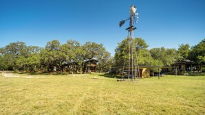 A grassy field with a windmill and several wooden houses. - Canyon Lake House w/ Porch, Views + Private Gazebo (Canyon Lake)