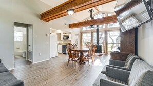 A spacious living area with a wooden ceiling, a dining table with chairs, a sofa, and a TV mounted on the wall. - Canyon Lake House w/ Porch, Views + Private Gazebo (Canyon Lake)