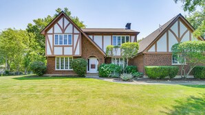 A Tudor-style house with a symmetrical facade, a central entrance, and a well-maintained lawn. - Bike & Kayak: Lakefront Prospect Heights Home (Prospect Heights)