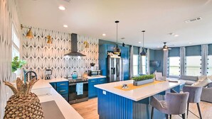 Una cocina moderna con una isla central, armarios azules y electrodomésticos de acero inoxidable.