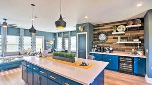 Una cocina moderna con armarios azules, una isla central, luces colgantes y un revestimiento de pared de madera.