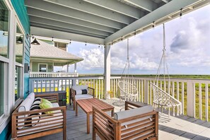 A covered outdoor area with wooden furniture, a hanging chair, and a view of the landscape. - Peaceful Galveston Getaway w/ Deck: Walk to Beach (Galveston)