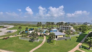 Un complexe hôtelier doté d’une piscine, de palmiers et offrant une vue sur l’océan.