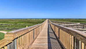 Une promenade en bois qui mène à une plage d’où l’on a une vue dégagée sur l’océan.