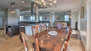 Une cuisine spacieuse dotée d’un grand îlot central, d’une table à manger en bois et de luminaires modernes.