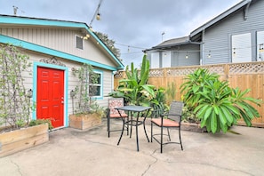 A patio with a red door, two chairs, and a table.