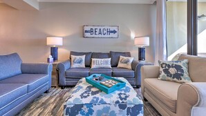 Una sala de estar con dos sofás, una mesa de centro y un letrero en la pared que dice "BEACH".