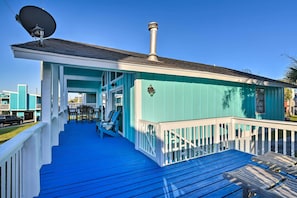 Un bâtiment turquoise avec une terrasse bleue, des balustrades blanches et une cheminée.