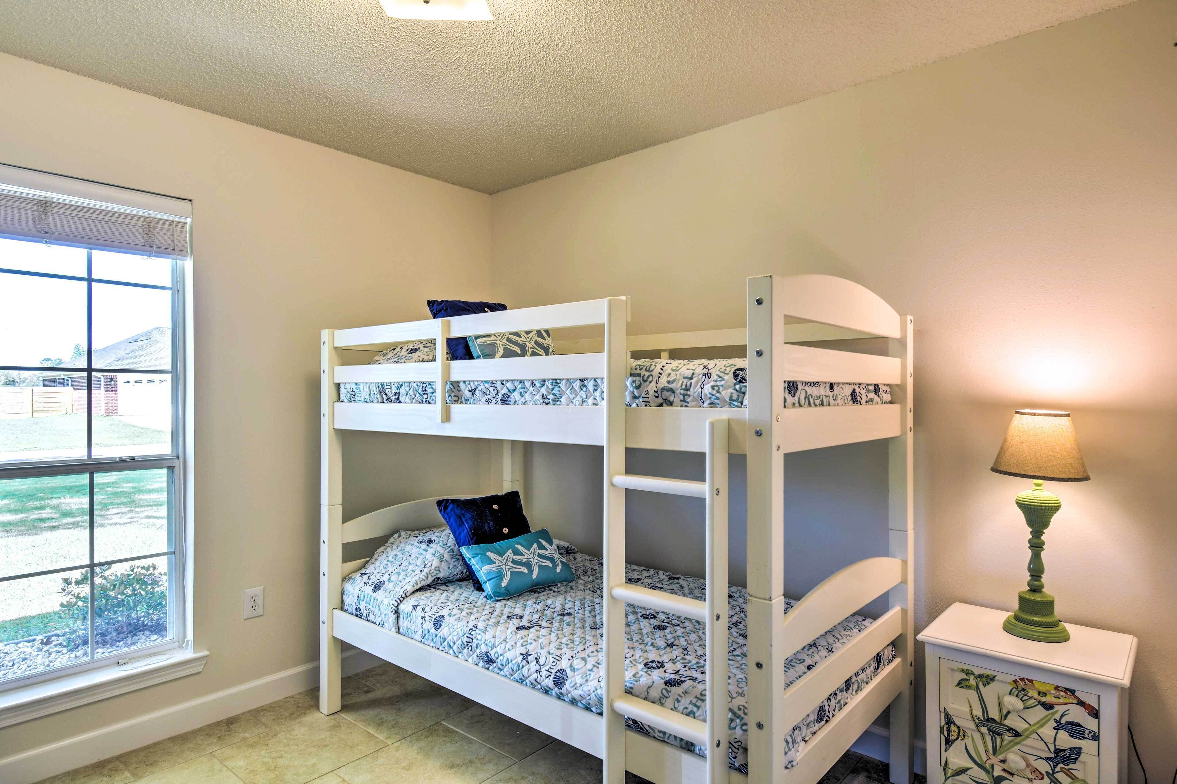 A bunk bed room with a window, a bedside lamp, and a small table.