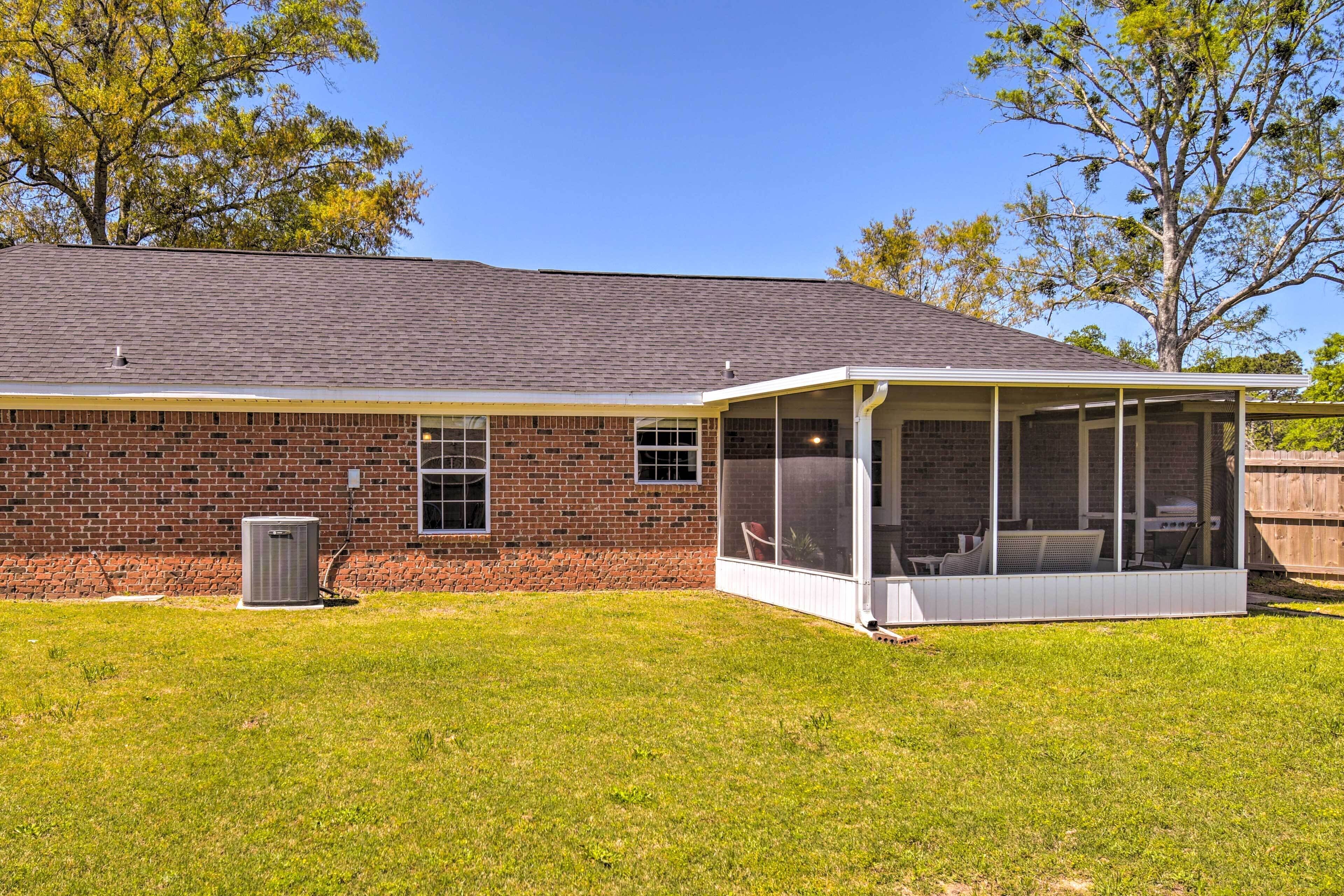 A brick house with a screened porch and a lawn.