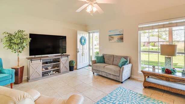 A living room with a television, sofa, and a ceiling fan.