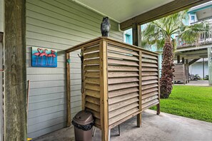 A wooden bench with a trash can beside it, a wooden fence, and a painting of flamingos on the wall. - < 1 Mi to Beach: Salty Dog House in Galveston! (Galveston)