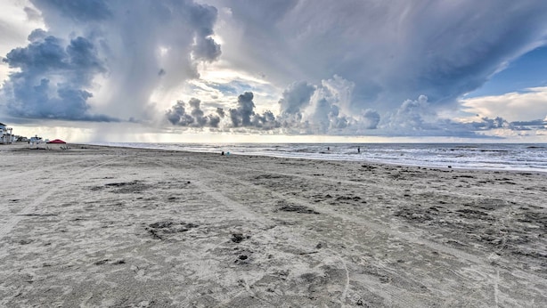 A beach with footprints and a red tent in the distance. - < 1 Mi to Beach: Salty Dog House in Galveston! (Galveston)