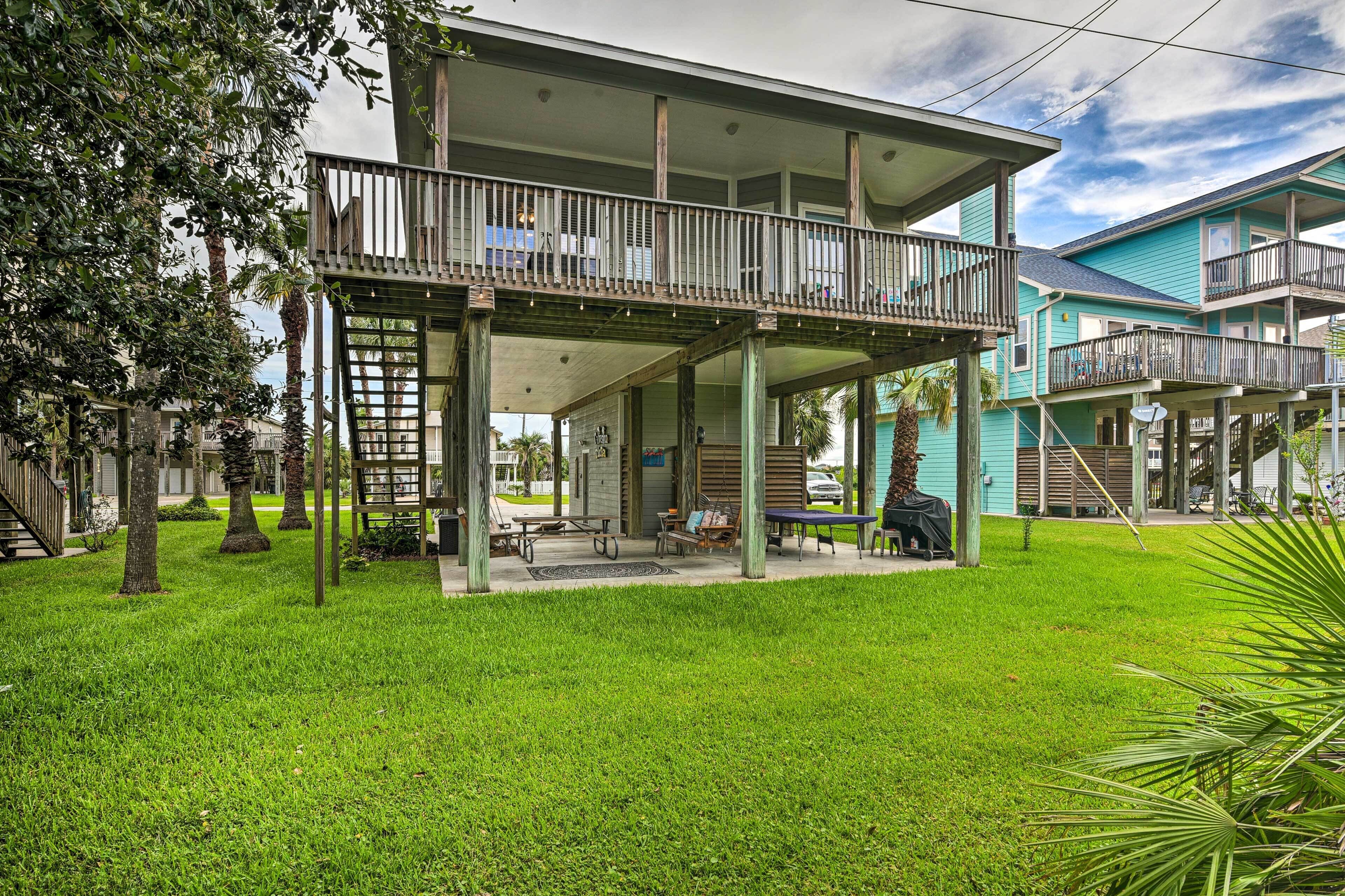 A two-story building with a balcony, outdoor seating, and a grassy yard.