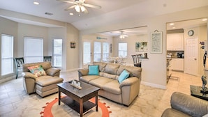 A spacious living room with a beige sectional sofa, a coffee table, and a ceiling fan. - < 1 Mi to Beach: Salty Dog House in Galveston! (Galveston)