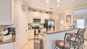 A modern kitchen with white cabinets, stainless steel appliances, a granite countertop, and a bar area with stools. - < 1 Mi to Beach: Salty Dog House in Galveston! (Galveston)