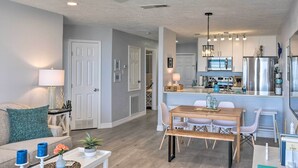 A modern kitchen with stainless steel appliances, a dining area with a wooden table and chairs, and a ceiling fan. - Ocean-view Balcony: Family Gem on Seawall Blvd! (Galveston)