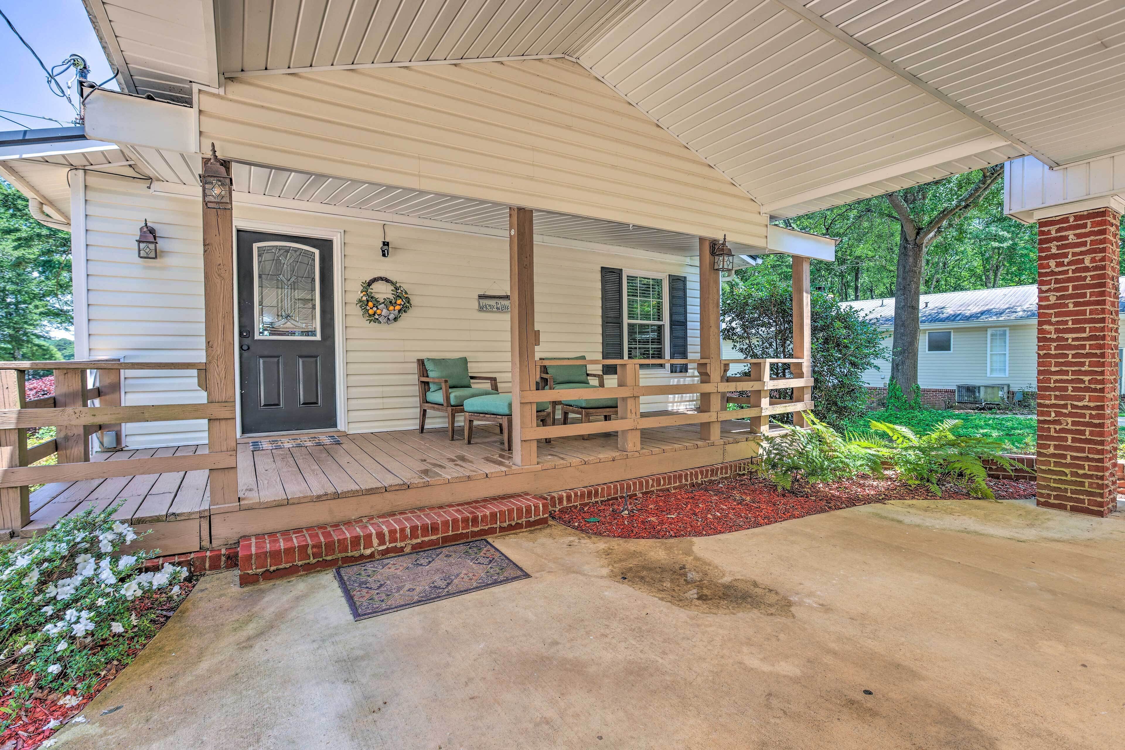 A covered porch with a wooden railing, a door, and a bench.