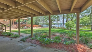 A covered patio area with a view of a lake and a brick building in the background. - The Lake Escape: Boat Dock, Fire Pit, Kayak! (Cropwell)