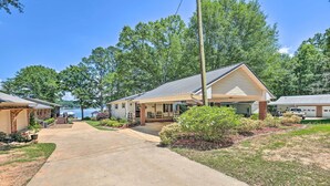 A row of single-story cabins with a covered porch, a concrete driveway, and a view of a lake. - The Lake Escape: Boat Dock, Fire Pit, Kayak! (Cropwell)