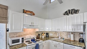 A kitchen with white cabinets, a microwave, stove, sink, and a toaster. - Galveston Beachfront House w/ Deck & Ocean Views! (Galveston)