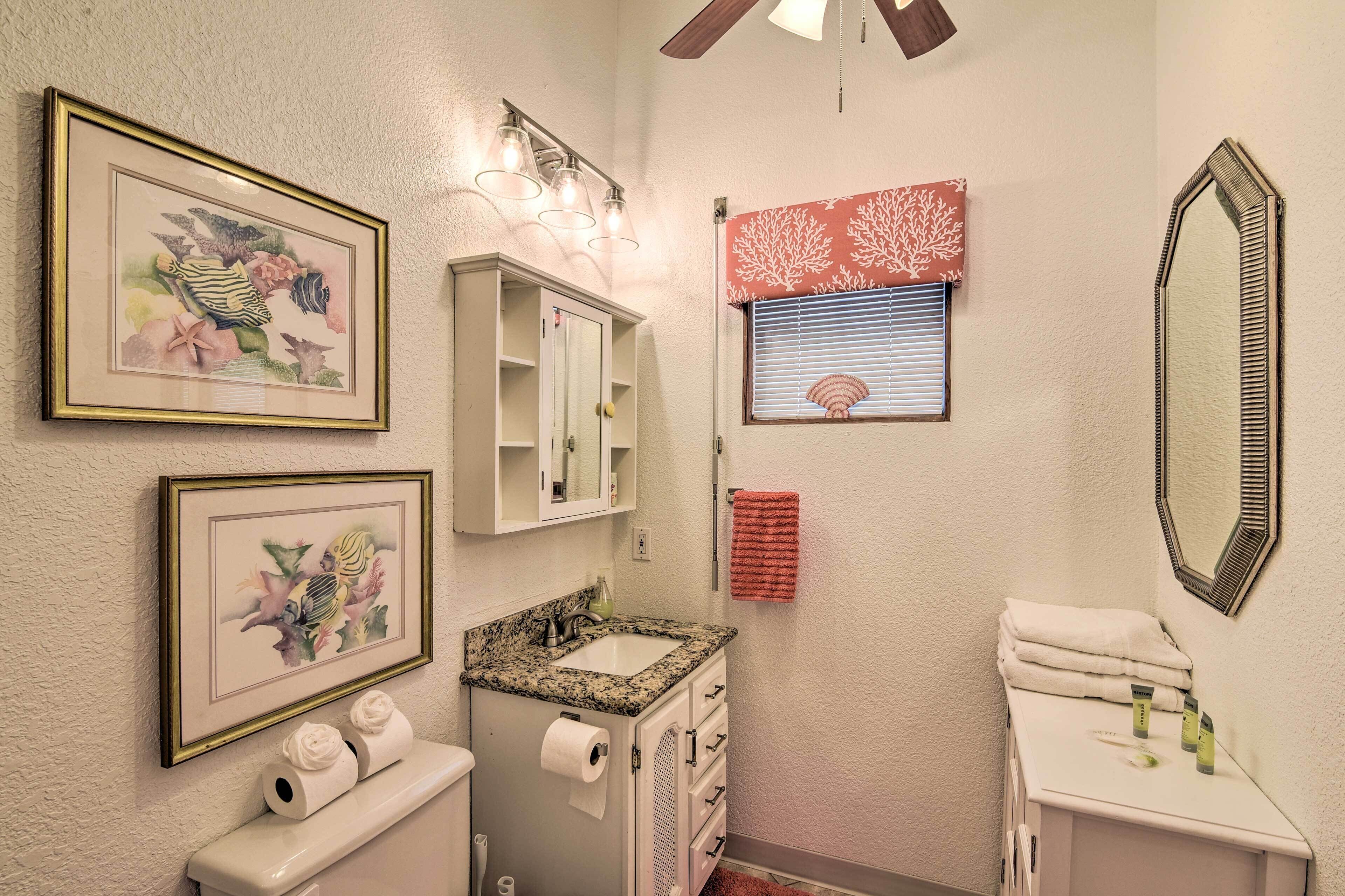 A bathroom with a sink, toilet, framed artwork, and a mirror.