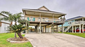A two-story building with a balcony, a covered parking area, and a palm tree.