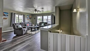 A spacious living room with a gray sectional sofa, a coffee table, and a ceiling fan.