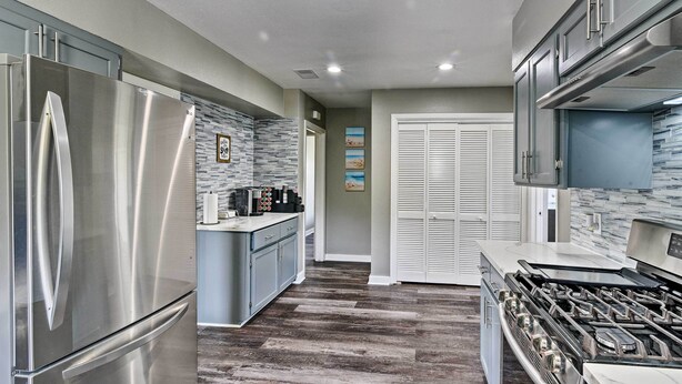 A modern kitchen with stainless steel appliances, a central island, and a view to the dining area.