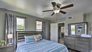 A bedroom with a bed, nightstand, dresser, and ceiling fan.