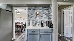 A modern kitchen with grey cabinets, a stone backsplash, and a coffee machine.