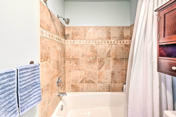 A bathroom with a bathtub, a shower, and a wooden cabinet.
