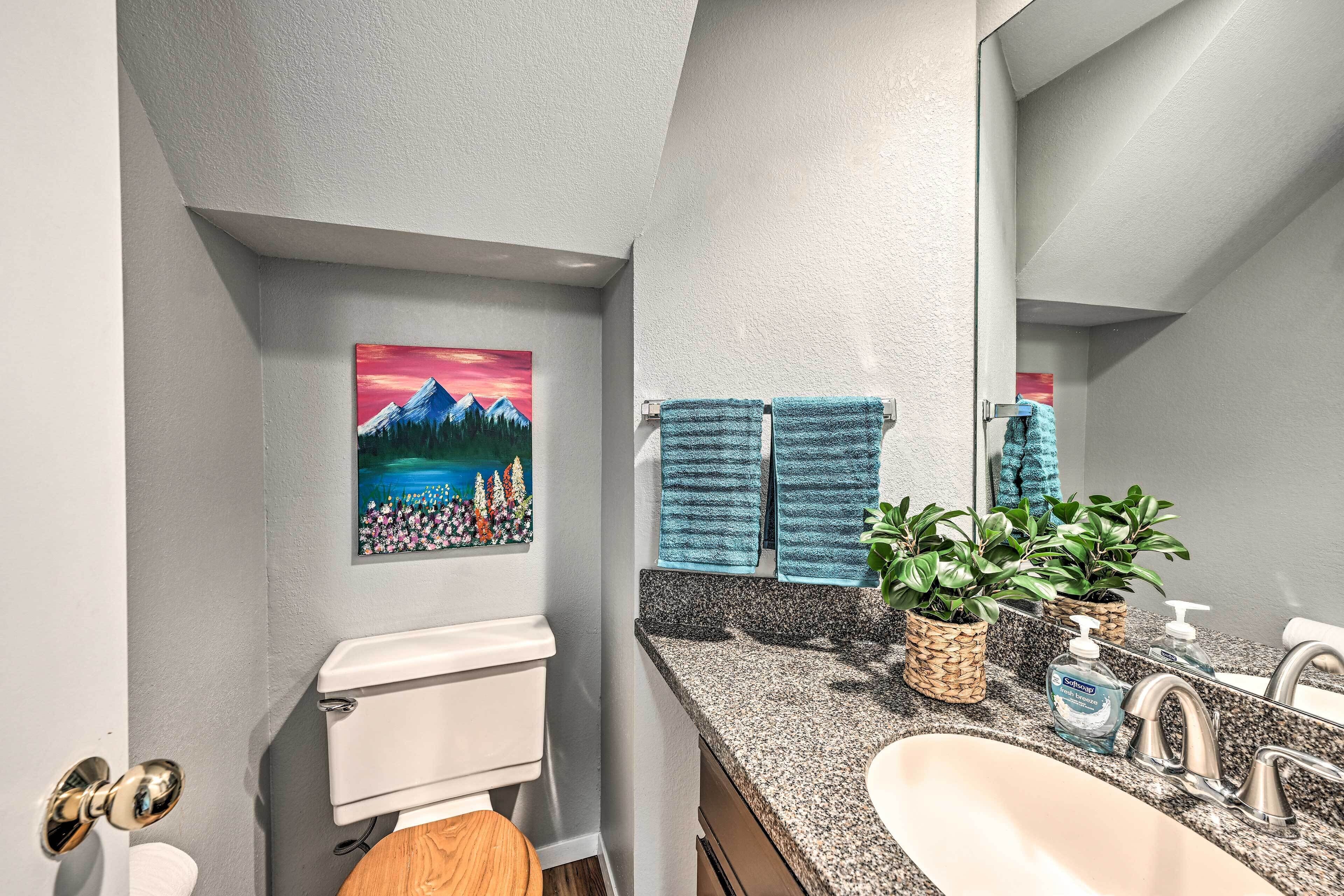 Ein Badezimmer mit Toilette, Waschbecken und einem Wandbild von einer Berglandschaft.