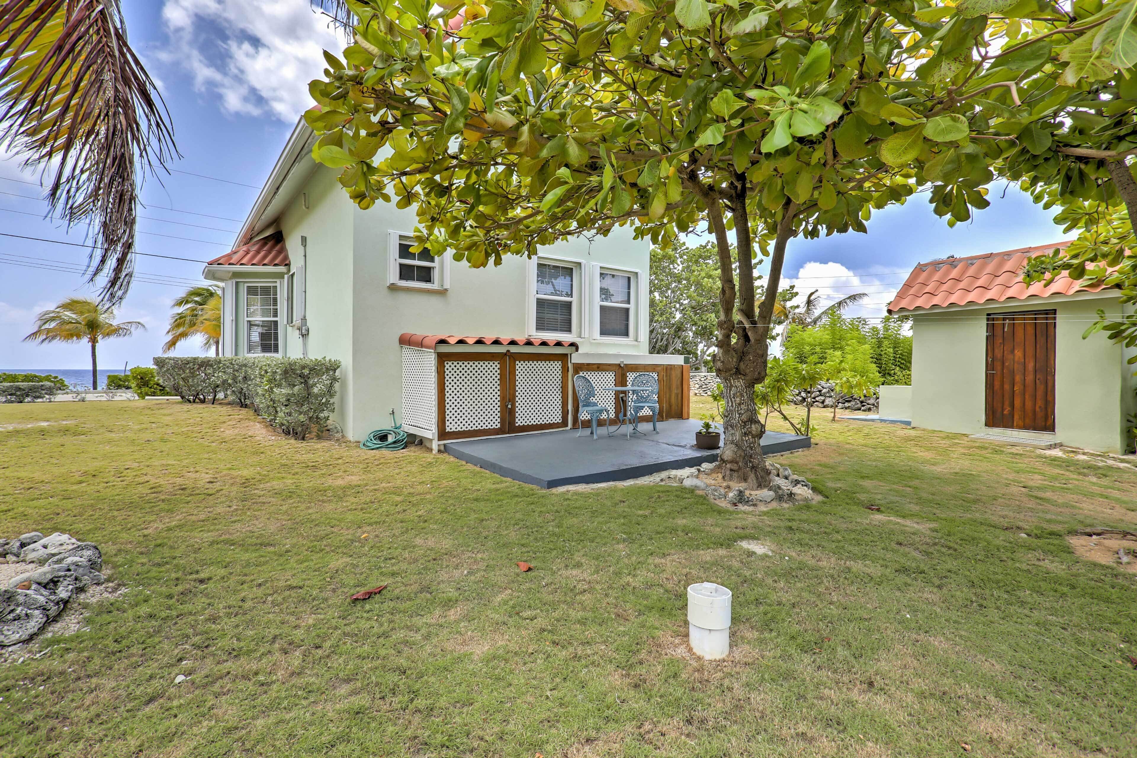 A house with a covered patio, a lawn, and a tree.