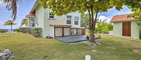 A house with a covered patio, a lawn, and a tree.