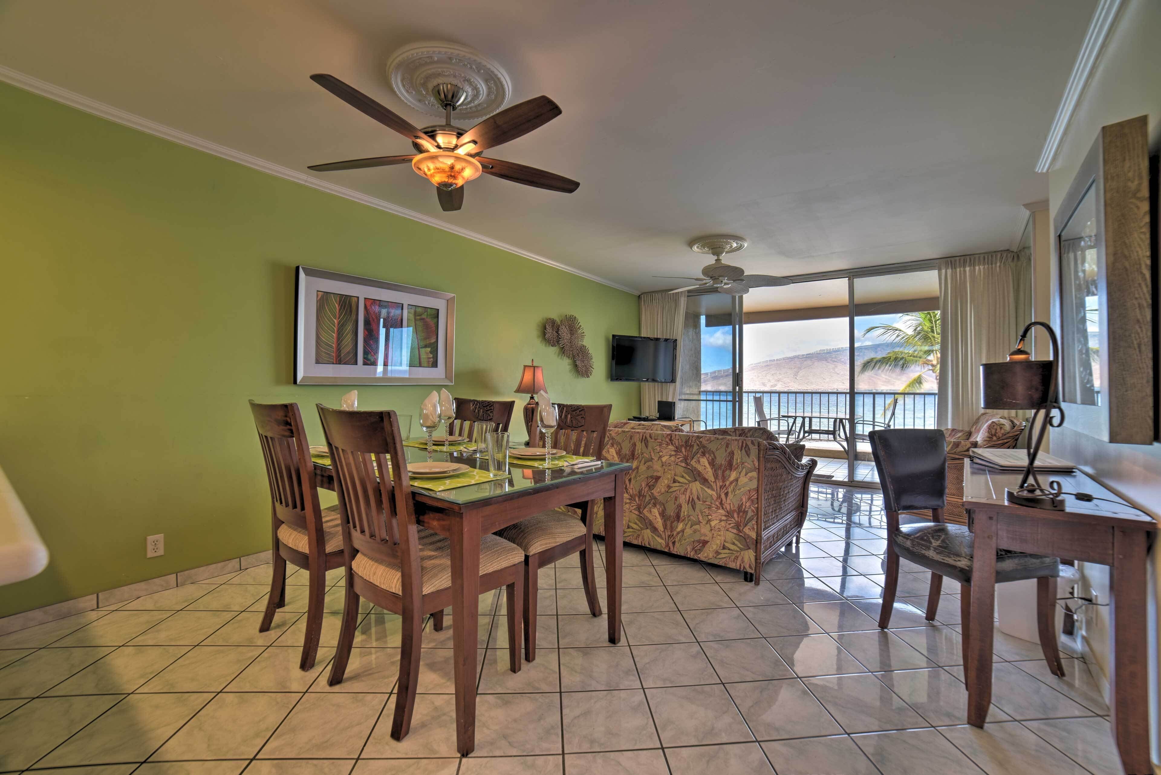 A dining area with a table set for four, a sofa, and a television.