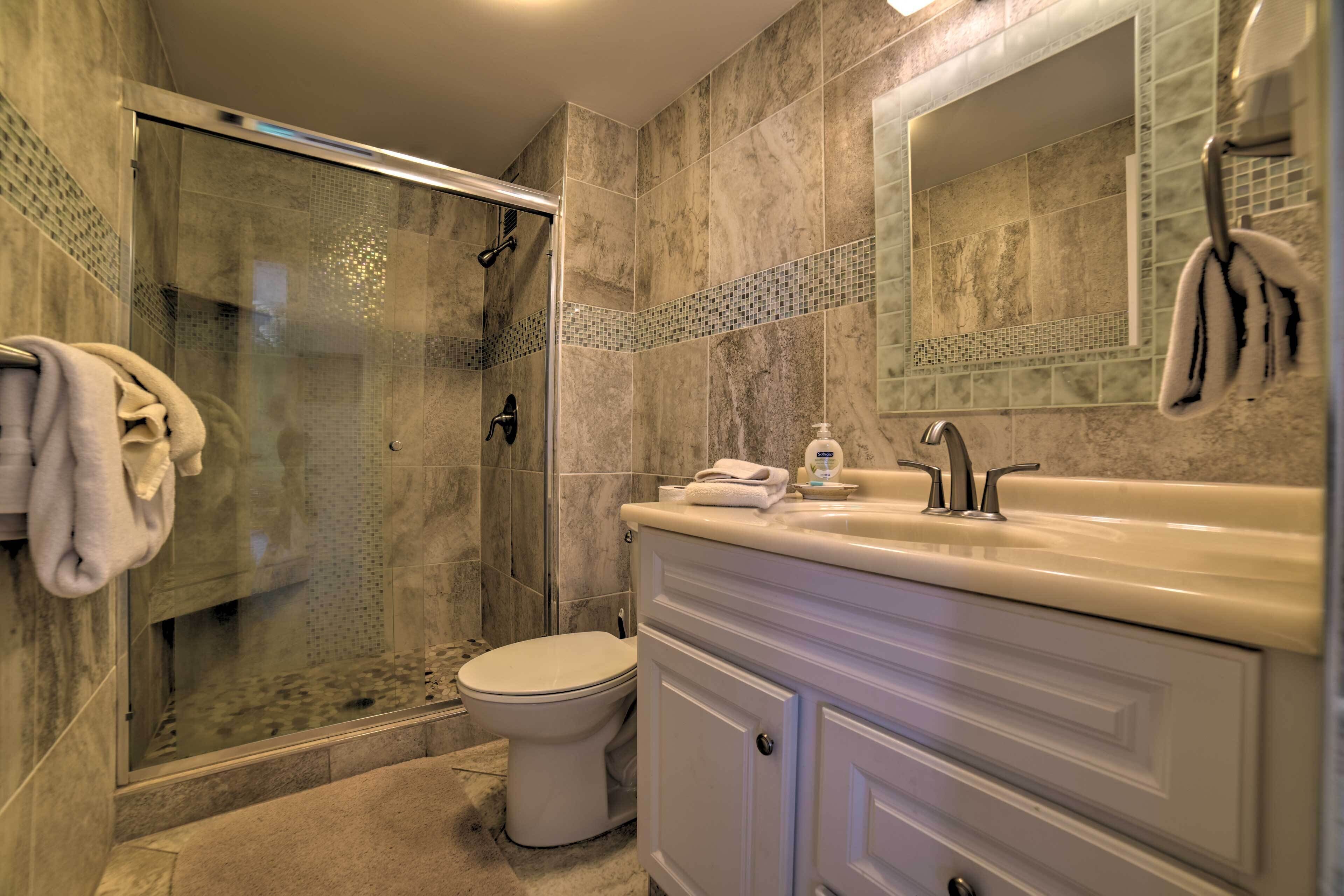 Een badkamer met een douchecabine, toilet en een wastafel met spiegel.